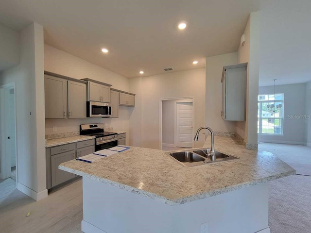 kitchen featuring kitchen peninsula, light carpet, appliances with stainless steel finishes, sink, and gray cabinets