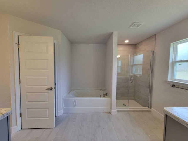 bathroom with vanity, hardwood / wood-style flooring, a textured ceiling, and separate shower and tub