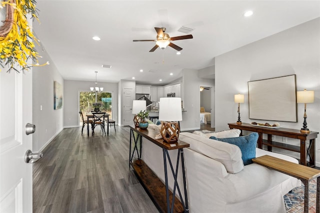 living room featuring ceiling fan with notable chandelier and dark hardwood / wood-style flooring