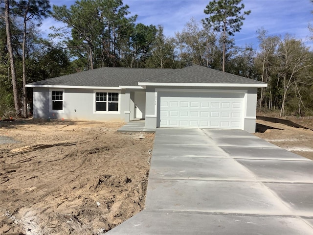 ranch-style home featuring a shingled roof, concrete driveway, an attached garage, and stucco siding