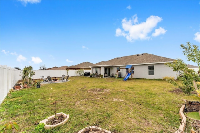 rear view of house featuring a playground, a fire pit, and a lawn