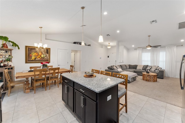 kitchen featuring a kitchen breakfast bar, light tile patterned floors, light stone countertops, a center island, and lofted ceiling