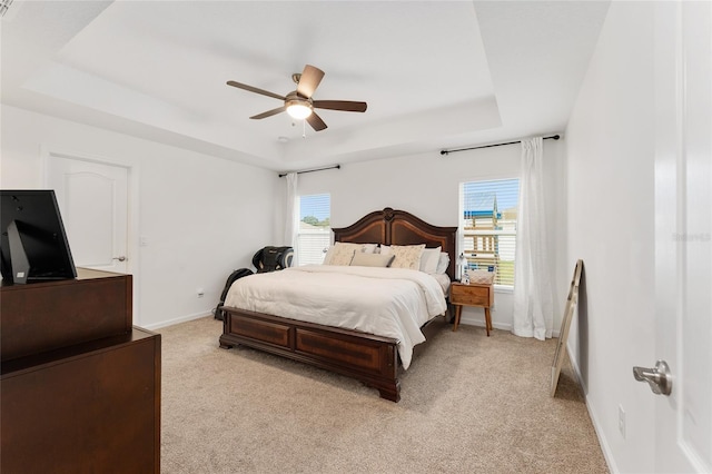 bedroom with multiple windows, ceiling fan, and a raised ceiling