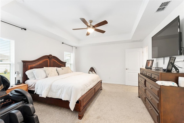 carpeted bedroom featuring ceiling fan and a raised ceiling