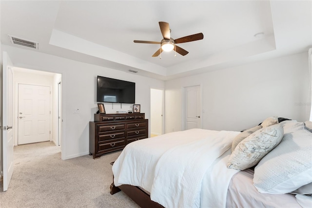 carpeted bedroom featuring ceiling fan and a tray ceiling