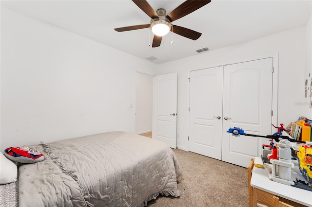 bedroom with a closet, ceiling fan, and light carpet