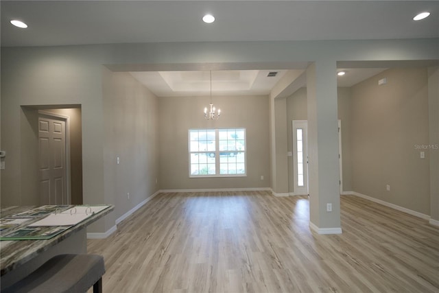 dining room featuring light hardwood / wood-style floors, a raised ceiling, and a notable chandelier