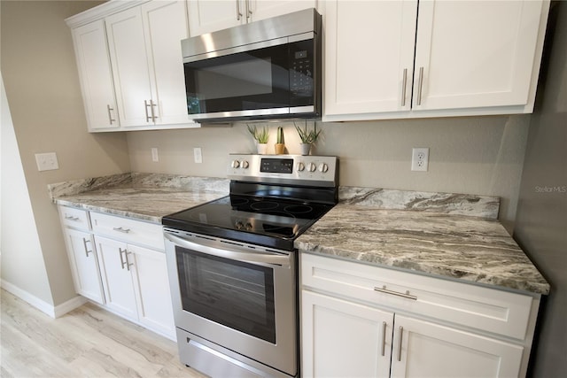 kitchen featuring white cabinetry, light stone counters, light hardwood / wood-style flooring, and appliances with stainless steel finishes