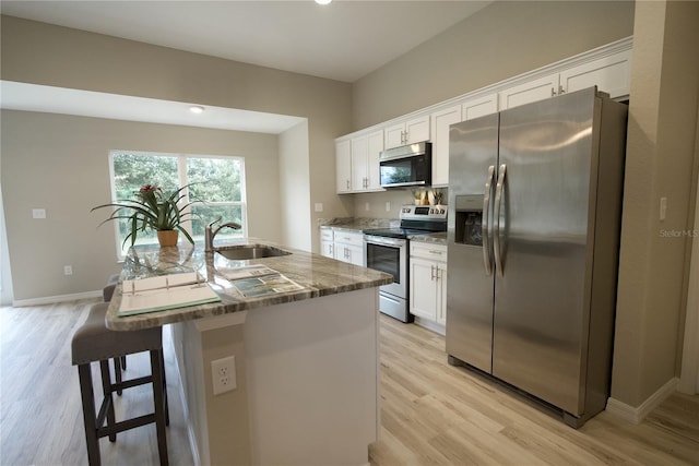 kitchen featuring sink, white cabinets, a breakfast bar, stainless steel appliances, and a center island with sink