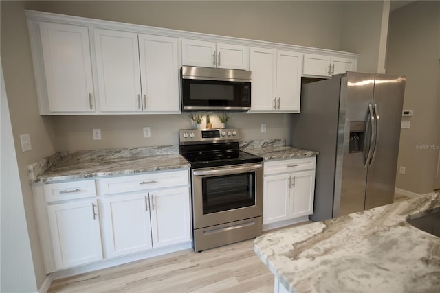 kitchen with light stone countertops, white cabinetry, and stainless steel appliances