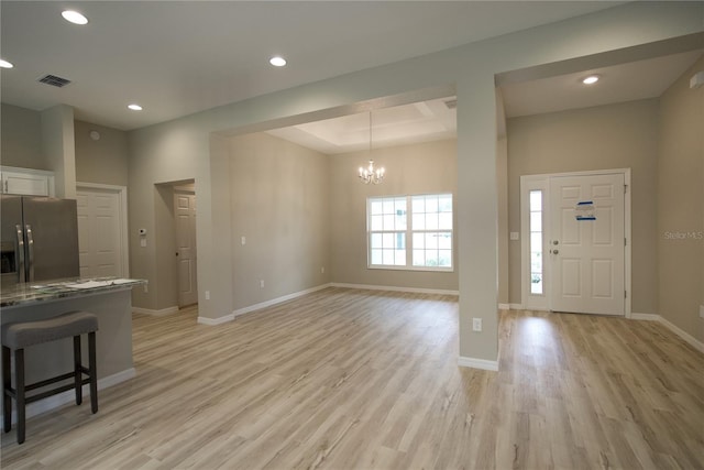 kitchen with white cabinetry, light hardwood / wood-style floors, a kitchen breakfast bar, stainless steel fridge, and a tray ceiling