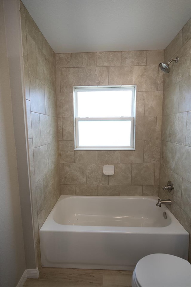 bathroom featuring toilet and tiled shower / bath combo