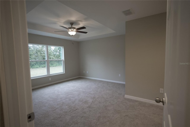 carpeted empty room with ceiling fan and a raised ceiling