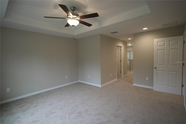 carpeted spare room featuring ceiling fan and a raised ceiling