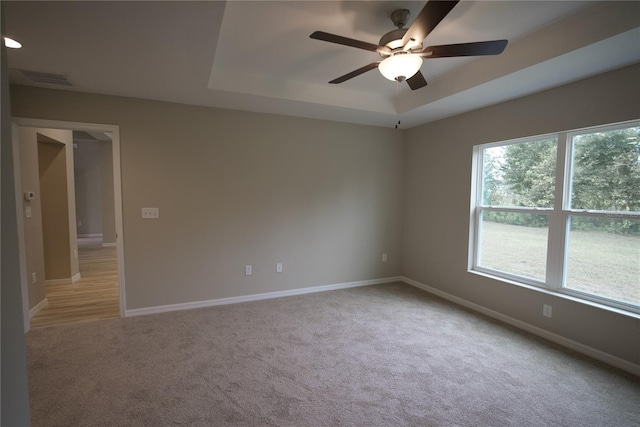 carpeted spare room featuring ceiling fan and a raised ceiling