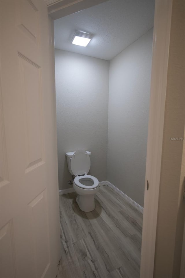 bathroom with toilet and hardwood / wood-style flooring