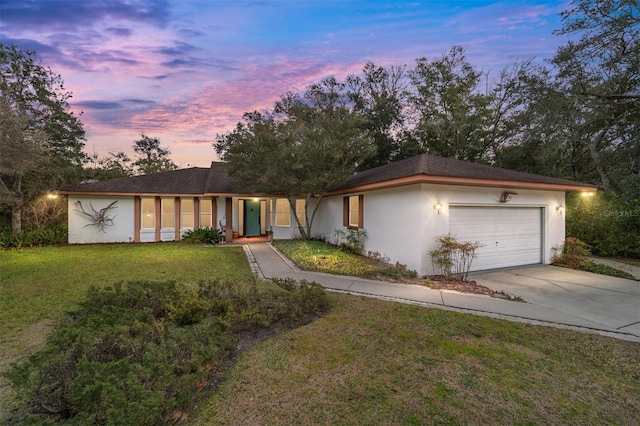 ranch-style home featuring a garage and a yard