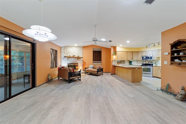 kitchen featuring light hardwood / wood-style floors, a fireplace, hanging light fixtures, stainless steel appliances, and light brown cabinets