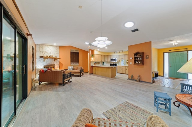 living room featuring a fireplace, light wood-type flooring, and vaulted ceiling