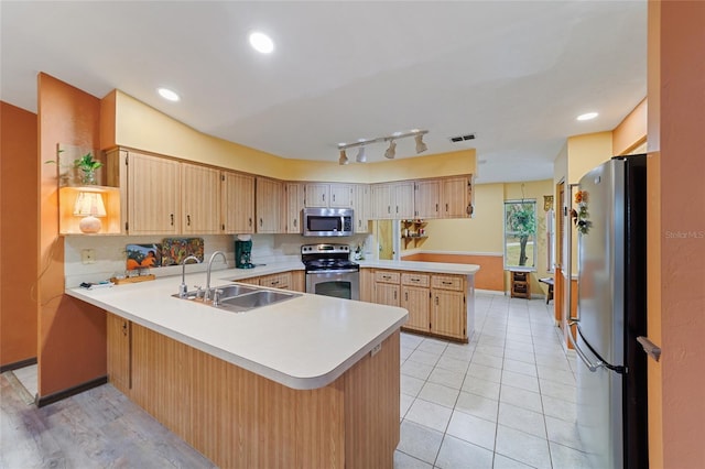 kitchen featuring kitchen peninsula, light brown cabinets, sink, light tile patterned flooring, and stainless steel appliances