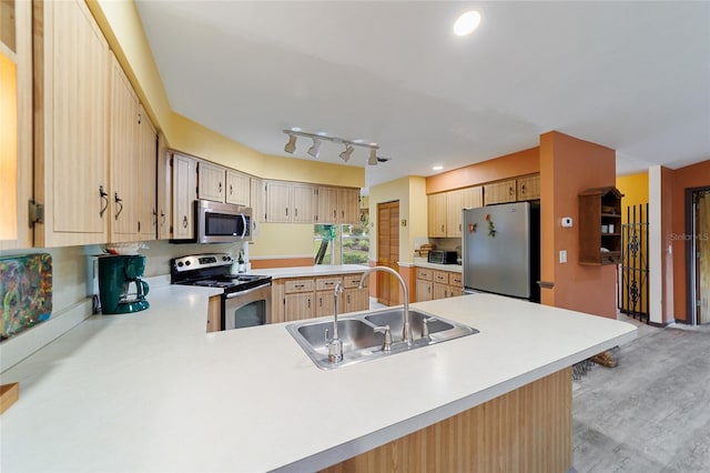 kitchen with appliances with stainless steel finishes, light brown cabinetry, sink, kitchen peninsula, and light hardwood / wood-style flooring