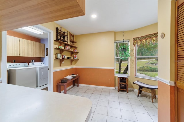 laundry room with washer and clothes dryer, light tile patterned floors, and cabinets