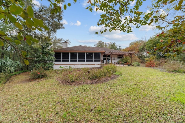 rear view of house with a pergola, a lawn, and a sunroom