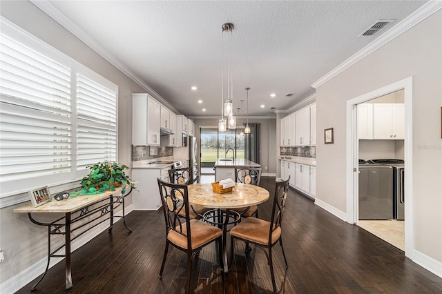 dining room featuring dark wood-type flooring, ornamental molding, and separate washer and dryer