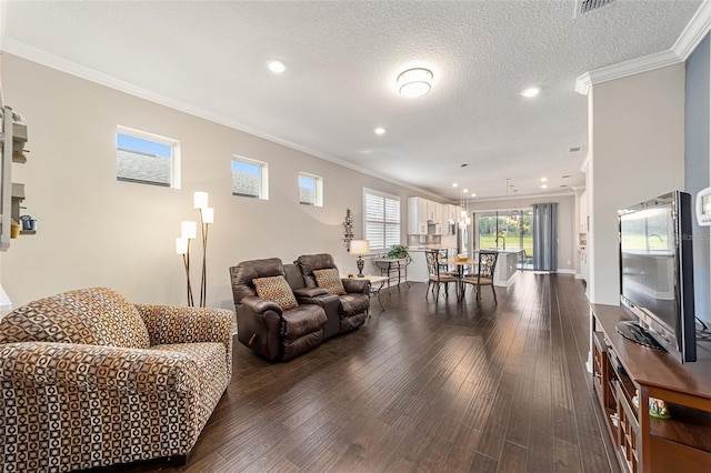 living room featuring dark wood-type flooring, ornamental molding, and a textured ceiling