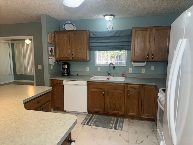 kitchen featuring sink, white appliances, and a textured ceiling