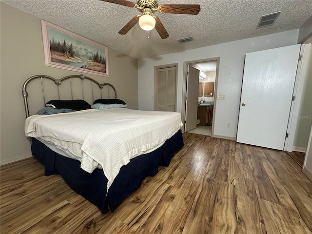 bedroom with a textured ceiling, wood-type flooring, ceiling fan, and ensuite bathroom