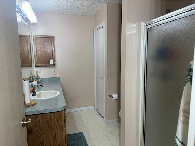 bathroom featuring vanity, an enclosed shower, and a textured ceiling