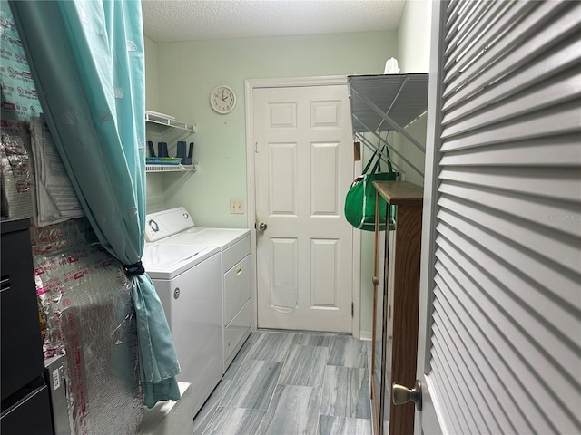 laundry area featuring a textured ceiling and washing machine and clothes dryer