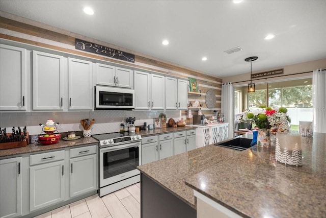 kitchen with white cabinets, pendant lighting, stainless steel range with electric stovetop, and dark stone countertops