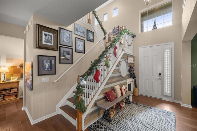 entrance foyer with hardwood / wood-style floors and a towering ceiling