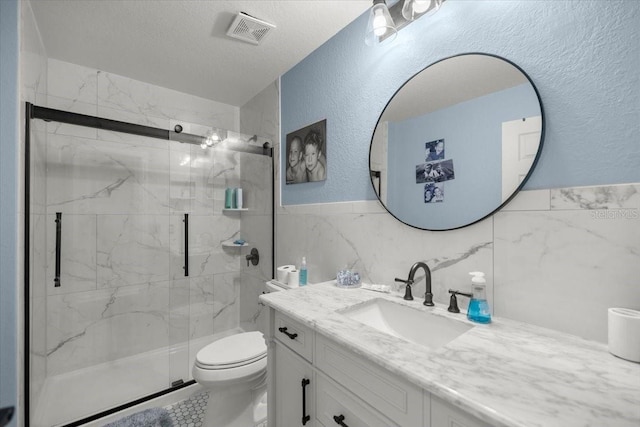 bathroom with a shower with shower door, toilet, a textured ceiling, tile walls, and vanity