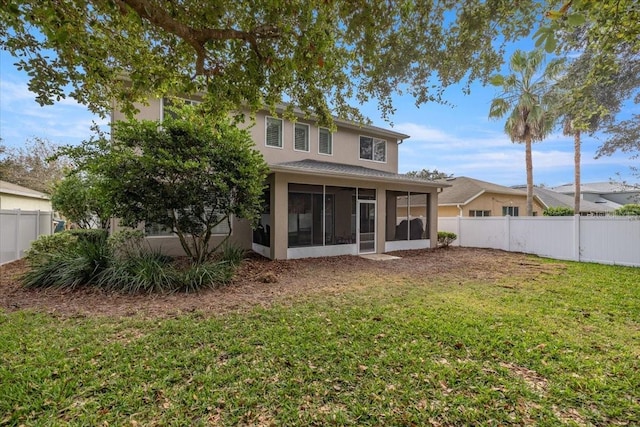 back of house featuring a lawn and a sunroom