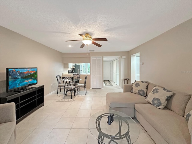 living room featuring ceiling fan, a textured ceiling, and light tile patterned floors