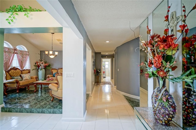 corridor featuring a notable chandelier, a wealth of natural light, a textured ceiling, and light tile patterned flooring