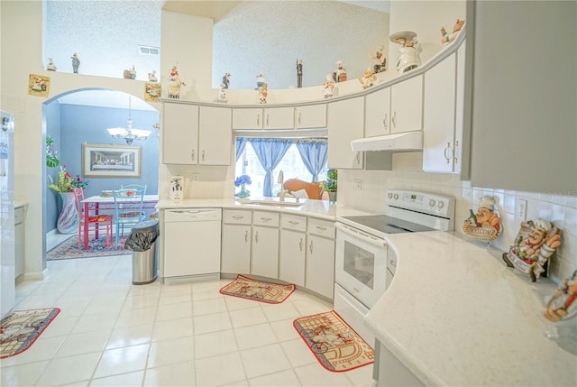 kitchen featuring sink, white appliances, white cabinets, and hanging light fixtures