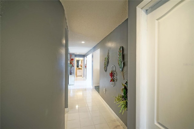 hallway with a textured ceiling and light tile patterned floors