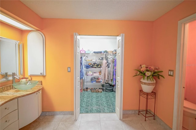 bathroom with vanity, toilet, a textured ceiling, and tile patterned flooring