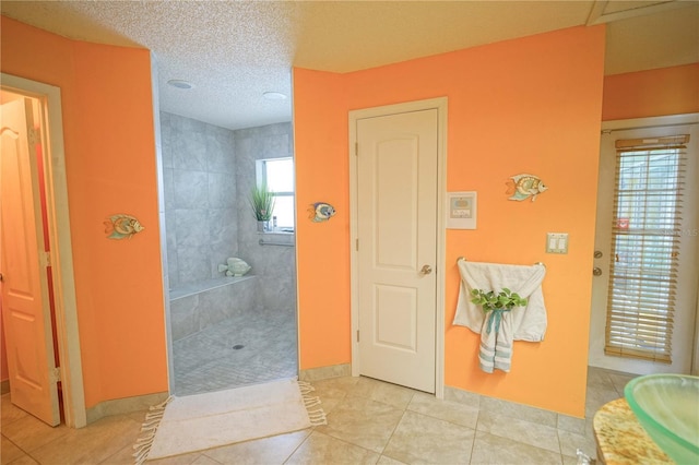 bathroom with a tile shower, a textured ceiling, and tile patterned floors