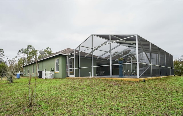 rear view of property with a lanai and a yard