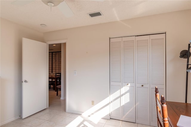 bedroom with a closet, visible vents, a textured ceiling, and light tile patterned floors