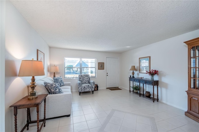 living room featuring a textured ceiling, baseboards, and light tile patterned floors