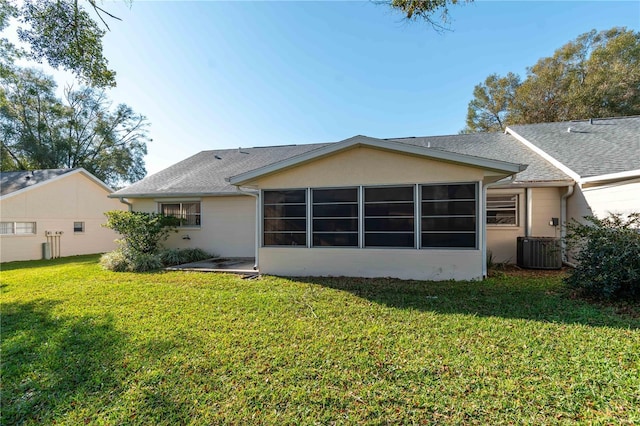 back of house featuring stucco siding, cooling unit, a lawn, and roof with shingles