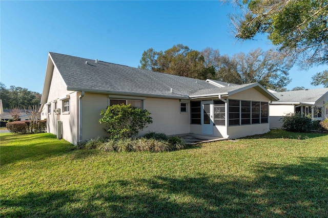 back of house featuring a sunroom, a shingled roof, and a yard