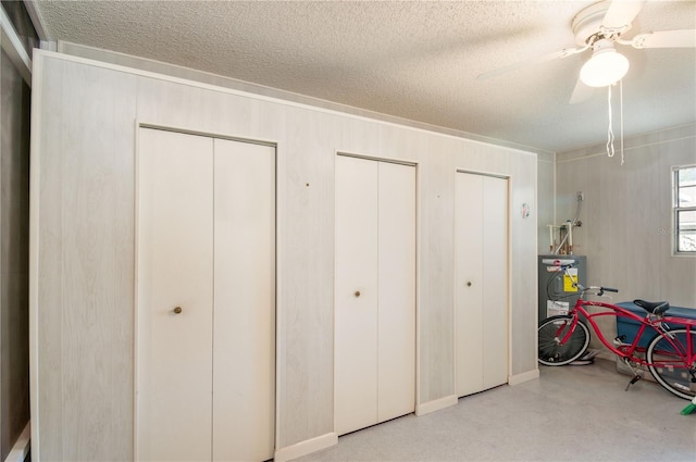 bedroom with ceiling fan, a textured ceiling, and two closets