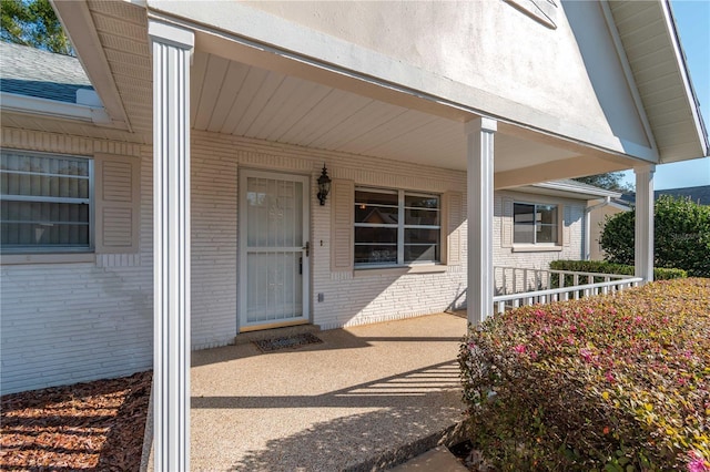 property entrance featuring a porch and brick siding